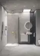Moderne Dusche mit einer großen, runden Kopfbrause in Brushed Gold von Ideal Standard. Der Raum ist minimalistisch gestaltet mit glatten, grauen Wänden und einem hellen Boden.